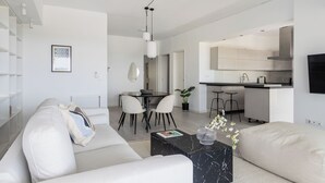 Ein modernes Wohnzimmer mit Sofa, Couchtisch und Essbereich mit Stühlen und Tisch.