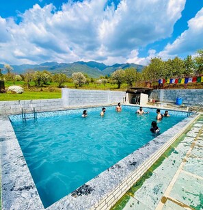 A swimming pool with a clear blue sky and mountains in the background. - Samyati valley retreat (Jogindarnagar)