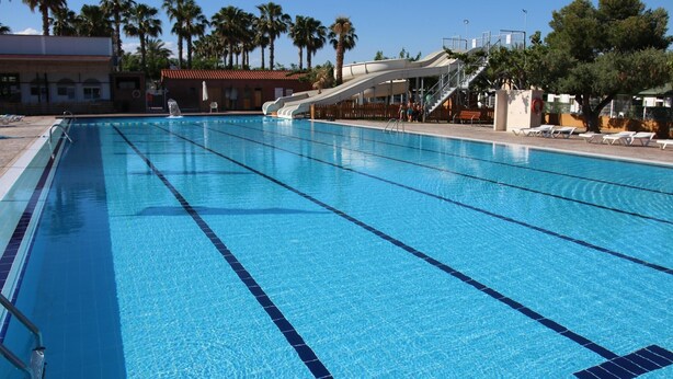 Una piscina con acqua cristallina, corsie delimitate e uno scivolo.