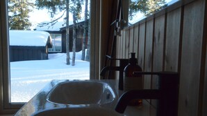 Un bagno con lavandino, erogatore di sapone e finestra.
