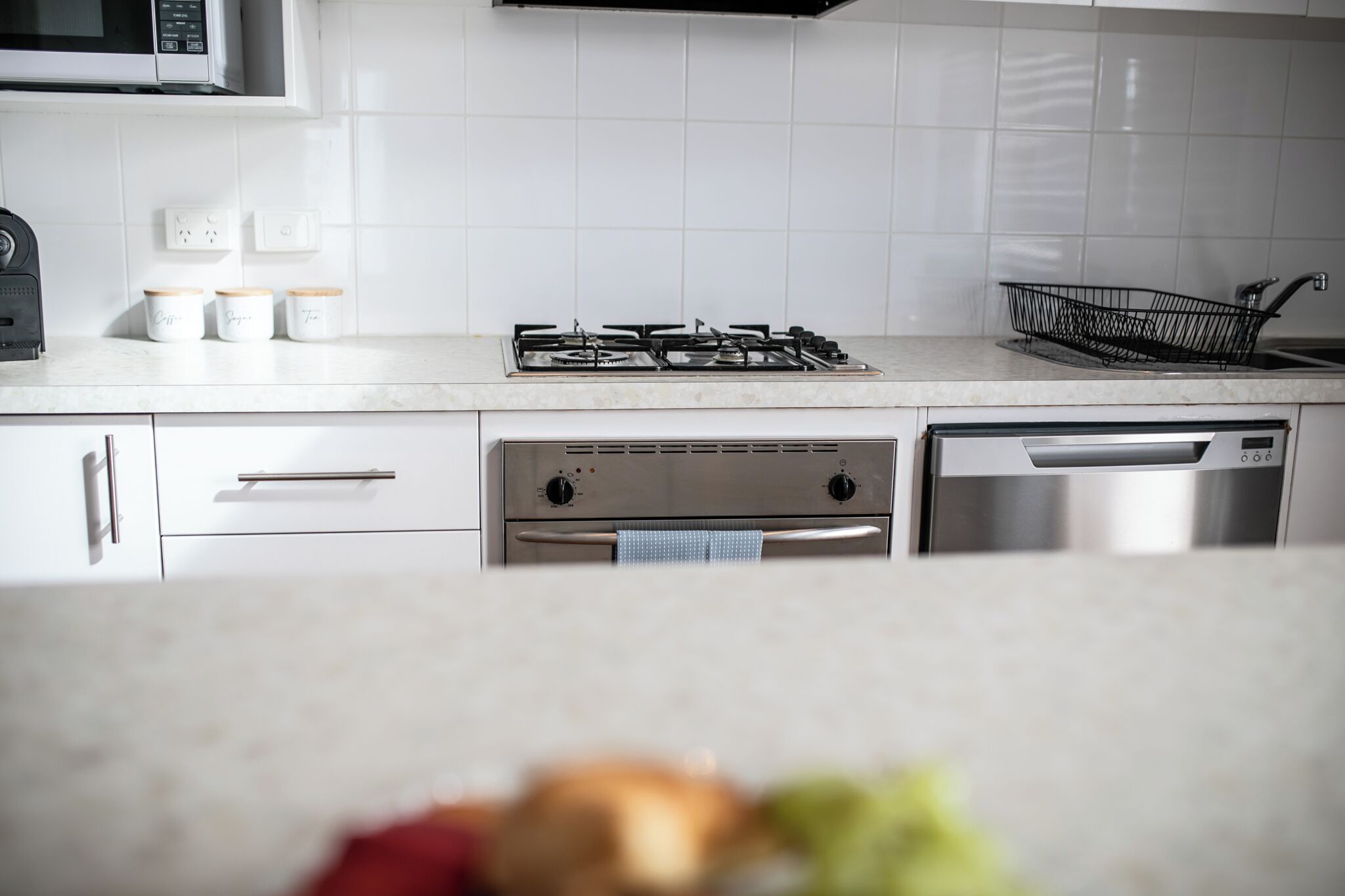 A modern kitchen with white cabinets, a gas stove, a microwave, and a dishwasher.