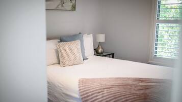 A neatly made bed with a white comforter and a striped throw blanket.