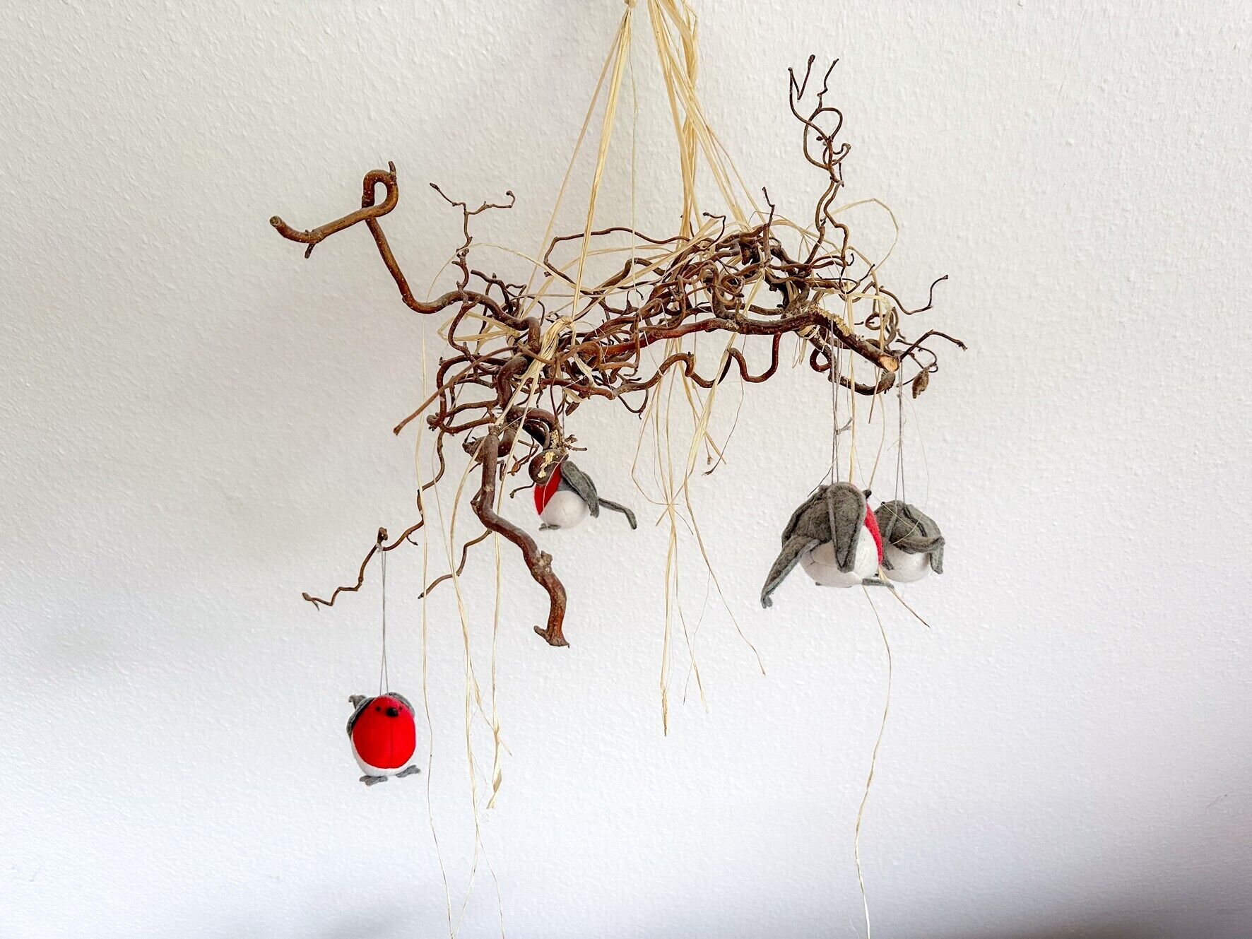 Decorazione a parete con rami e figure di uccelli pendenti.