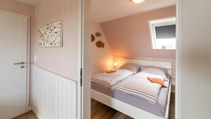 Un dormitorio con cama, ventana, puerta y un adorno en la pared.