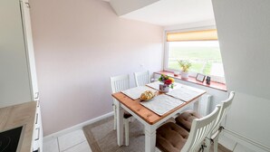 Un comedor con una mesa, sillas, vistas al exterior y una ventana con persianas.