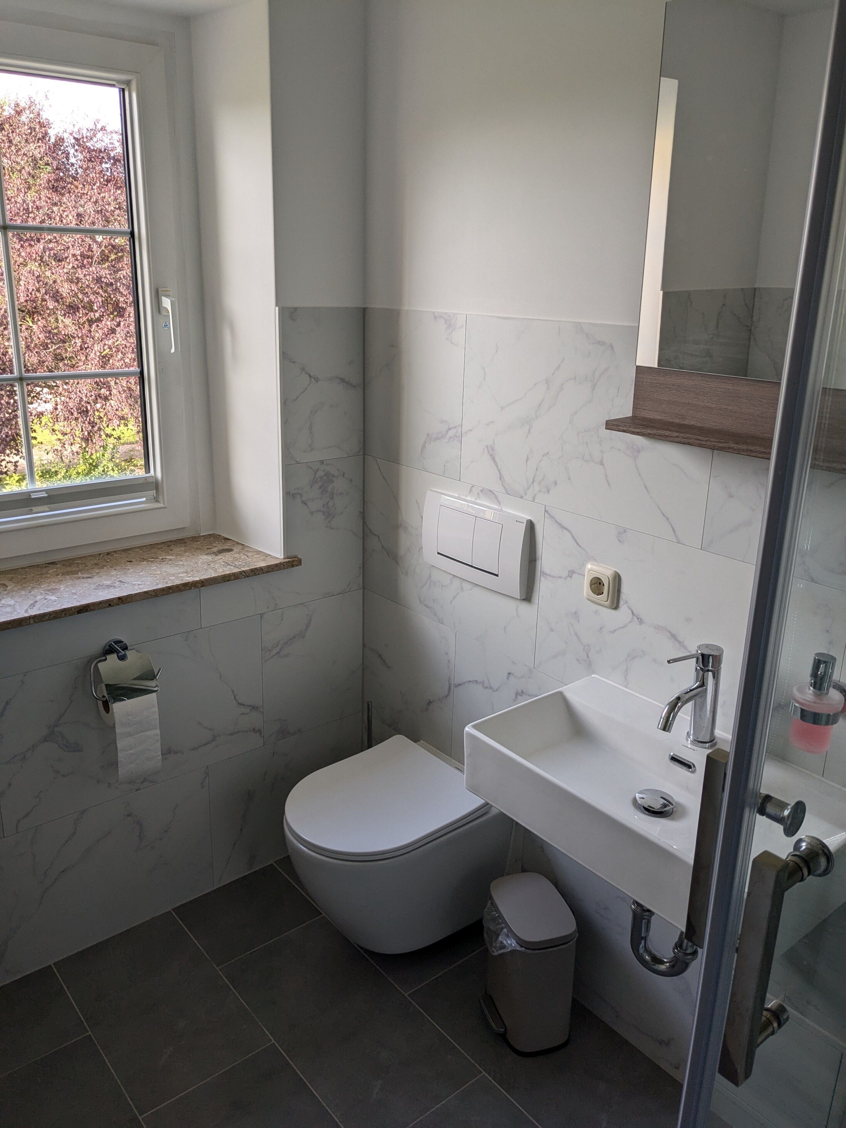 A bathroom with a toilet, sink, and window.