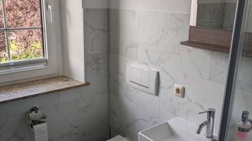 A bathroom with a toilet, sink, and window.