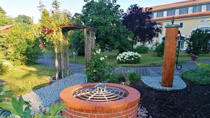 A circular brick fire pit with a metal spiral design, surrounded by a gravel path and greenery. - Apartment 'Ferienwohnung Wiesenduft' with Shared Pool, Shared Terrace and Wi-Fi (Klipphausen)