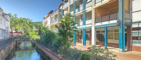 Un hotel con varios balcones, un canal en primer plano y un puente peatonal.