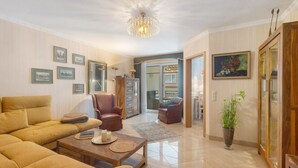 Ein Wohnzimmer mit Sofa, Sesseln, Couchtisch und einer Deckenleuchte.