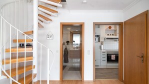 A modern interior with a spiral staircase, a kitchen, and a wooden door. - Apartment 'Fewo Christi' with Wi-Fi (Weißensberg)