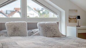 A bedroom with a bed, fluffy pillows, a window, and a bedside table with a lamp. - Apartment 'Fewo Christi' with Wi-Fi (Weißensberg)