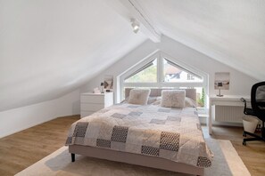 Un dormitorio con una cama grande, una ventana, un escritorio y una silla.