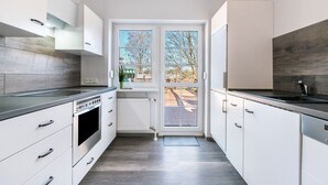 Eine moderne Küche mit weißen Schränken, einem eingebauten Backofen und einem großen Fenster.