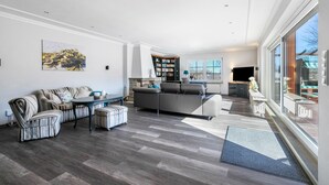 Ein geräumiges Wohnzimmer mit einem Ecksofa, einem Esstisch und einer Küche im Hintergrund.