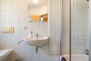 A bathroom with a sink, mirror, toilet, and glass shower enclosure. - Room 'Einzelzimmer B' with Shared Terrace and Wi-Fi (Meißen)