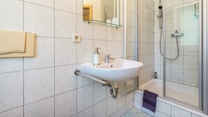 A bathroom with a white sink, a glass shower enclosure, and a mirror above the sink.