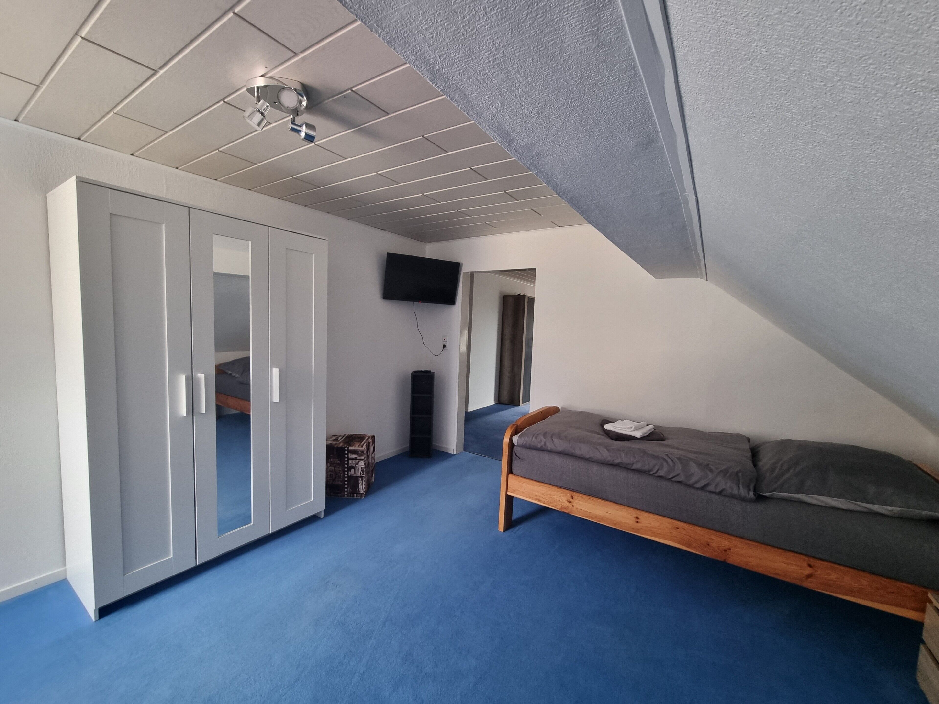 Une chambre avec un lit superposé, une armoire, un téléviseur à écran plat et un ventilateur de plafond.