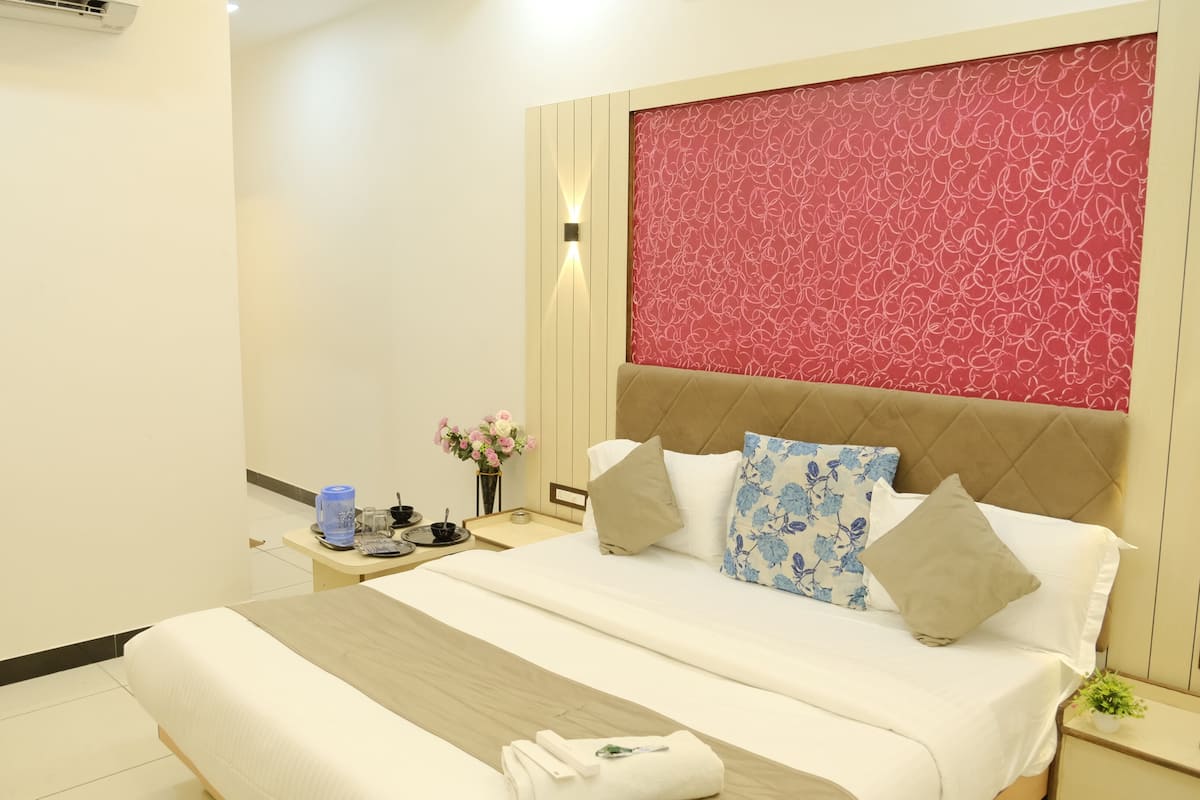A hotel room with a bed, bedside table, and a wall with a patterned design.
