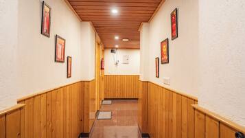 A hallway with wooden paneling, framed pictures on the walls, and a fire extinguisher mounted on the wall.