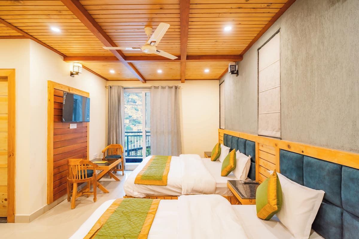 Habitación de hotel con dos camas, muebles de madera, ventilador de techo y vistas al exterior.