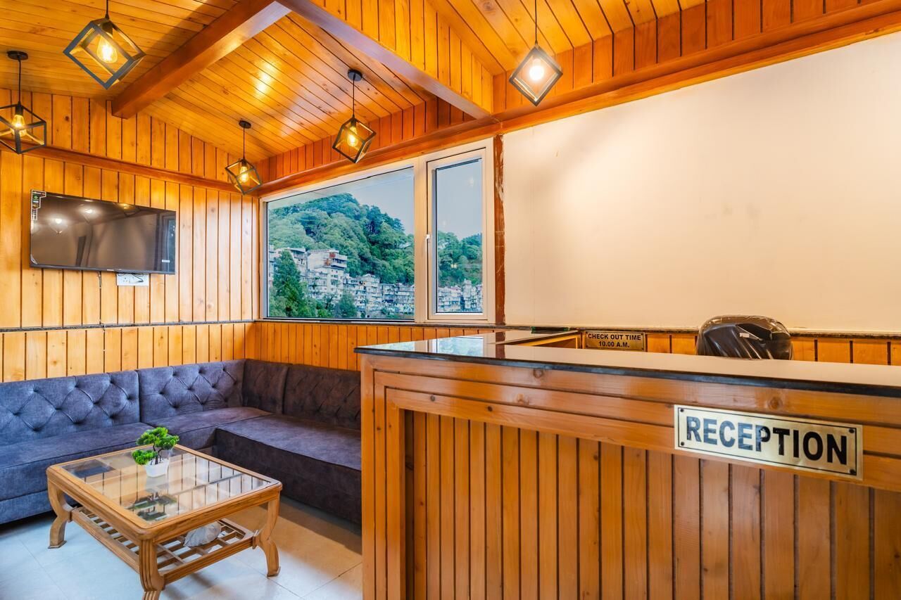 A reception area with a wooden reception desk, a sofa, and a television.