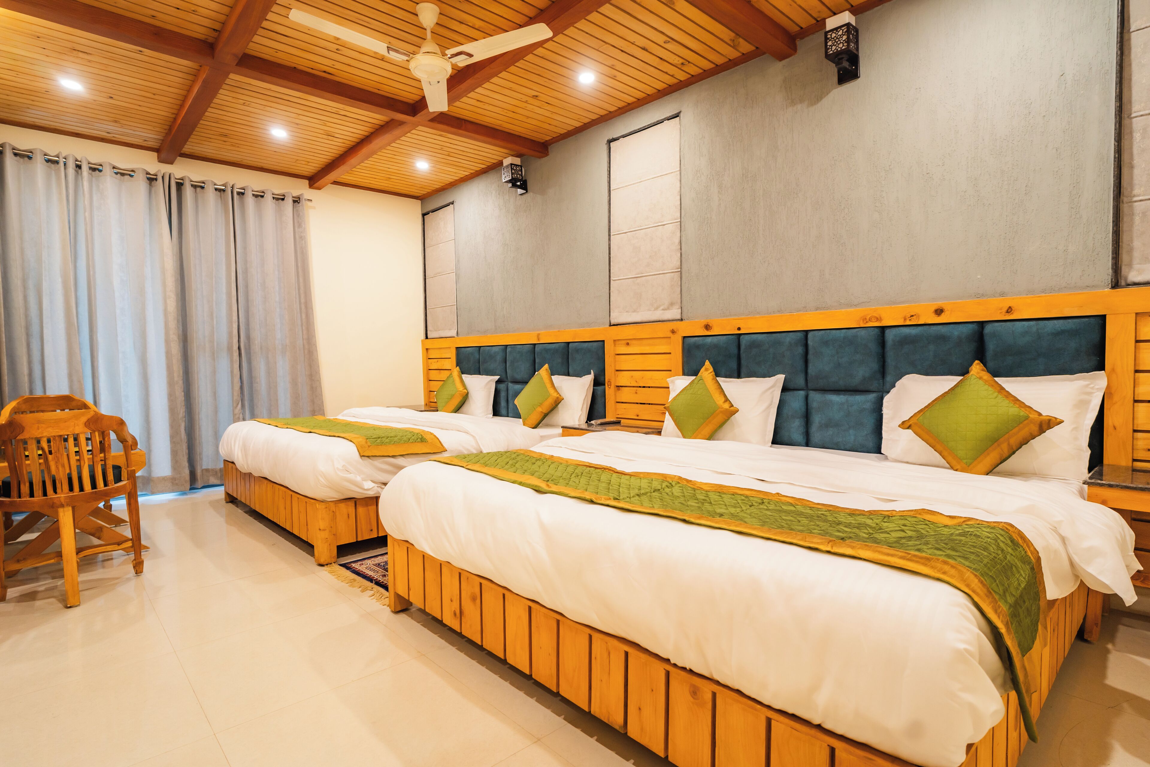 A hotel room with two wooden beds, a wooden chair, and a ceiling fan.
