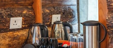 A kitchen counter with a coffee maker, kettles, and mugs.