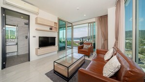 Ein modernes Wohnzimmer mit Flachbildfernseher, braunem Ledersofa und Glastisch.