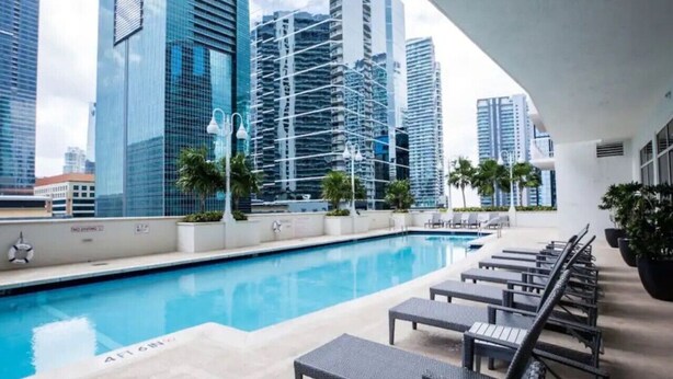 A rooftop pool with lounge chairs and a cityscape view. - Cozy 4BR Apt@Brickell, free parking (Miami)