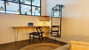 Ein gemütliches Zimmer mit Schreibtisch, zwei Stühlen, einem Teppich und einem Bett mit Kissen.