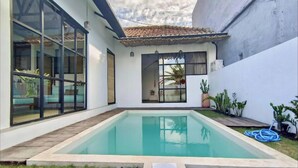 Ein modernes Haus mit Swimmingpool, großen Fenstern und einem Ziegeldach.