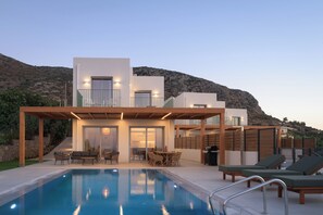 Un espace moderne aménagé au bord de la piscine, comprenant une piscine, des chaises longues et un coin repas.