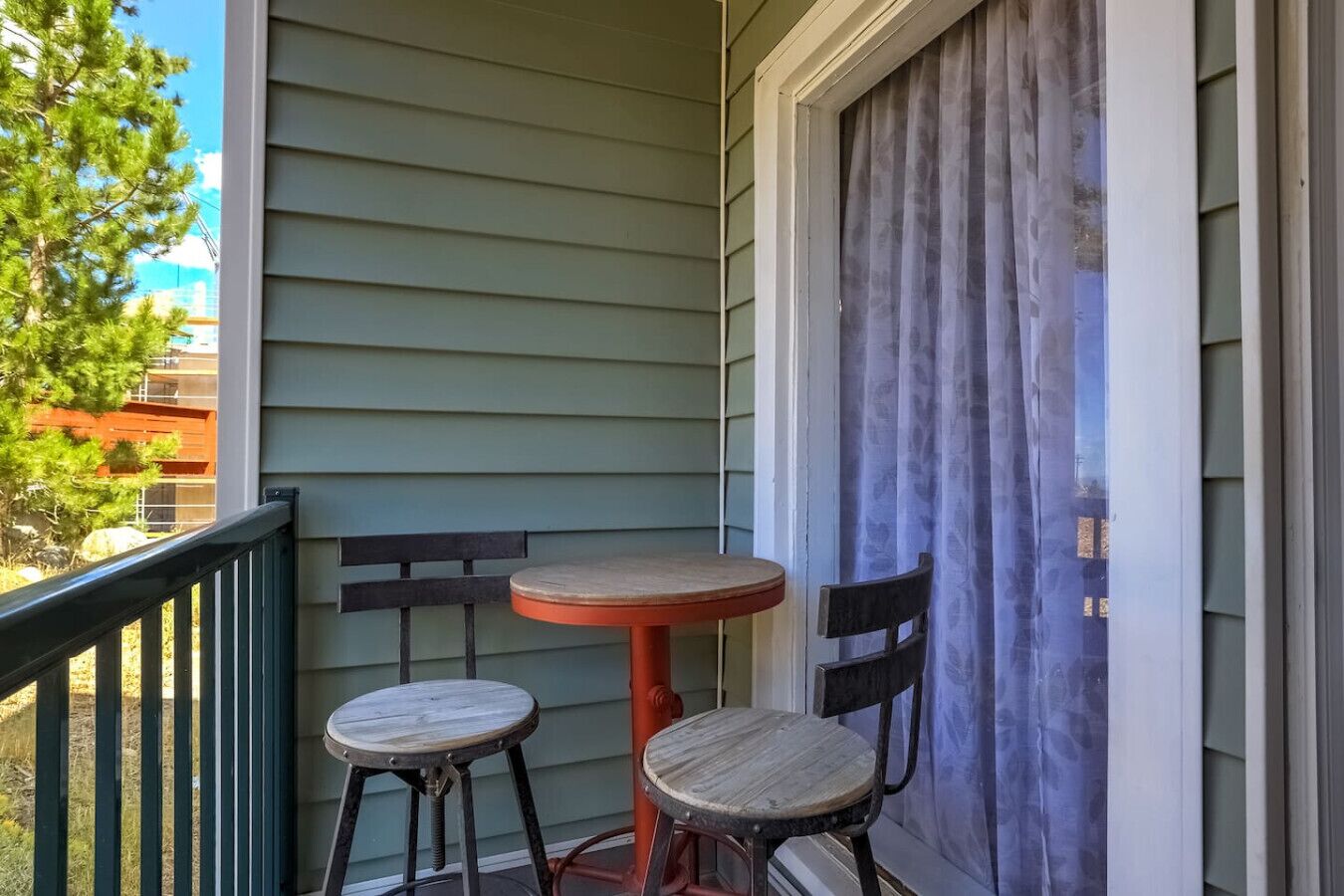 A small balcony with two wooden chairs and a table.