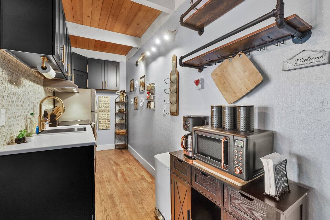 Una cocina con techo de madera, microondas integrado y cafetera.