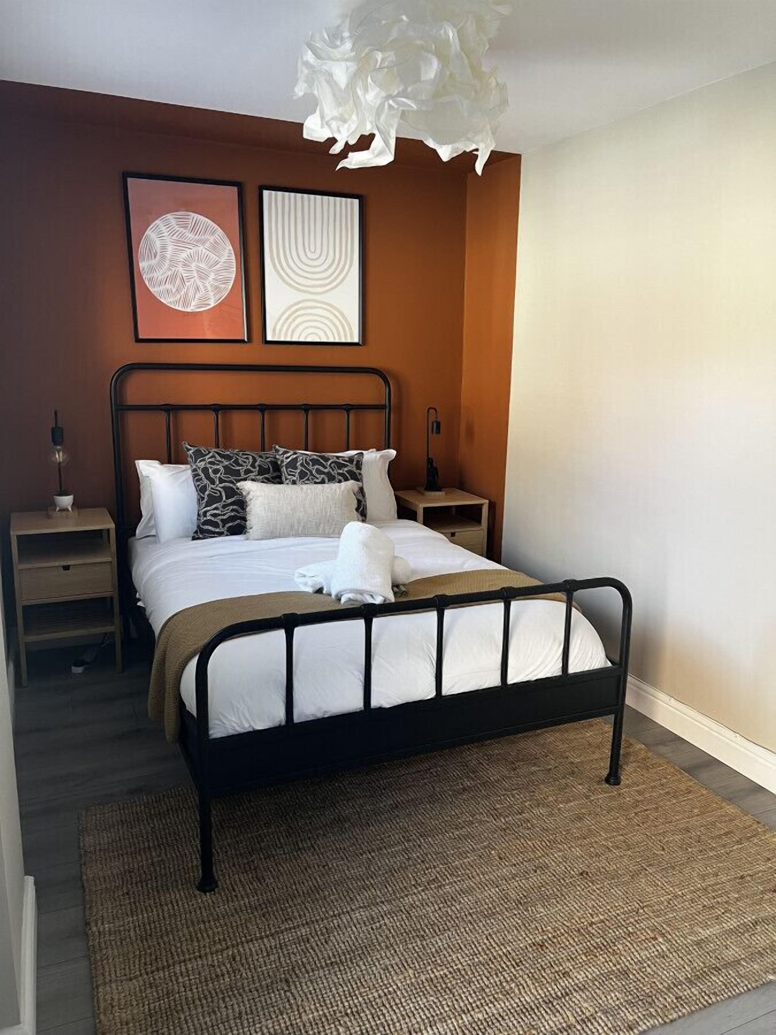 Ein ordentlich eingerichtetes Schlafzimmer mit Bett, Nachttischen und Wandbildern.