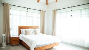 Un dormitorio amplio con una cama grande, cabecera de madera y una mesita de noche.