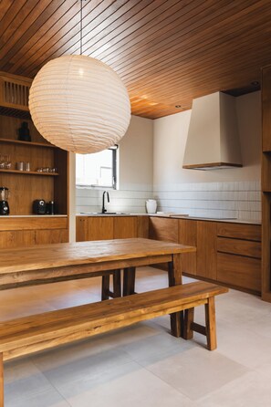 Enjoy cooking in this well-equipped kitchen with a wooden table, hanging light fixture, and cabinetry.