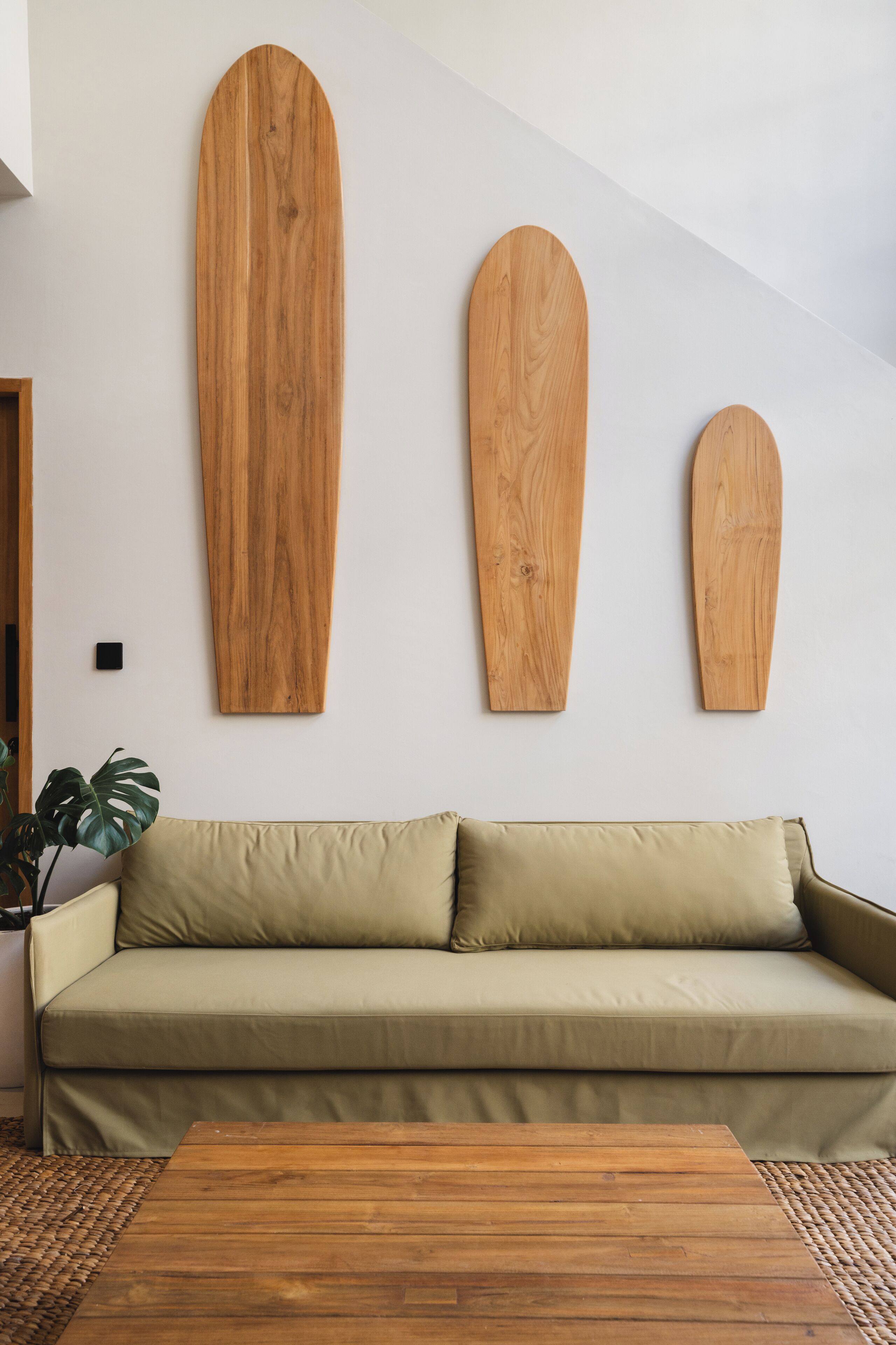 Una habitación con un sofá y tres tablas de surf de madera en la pared.