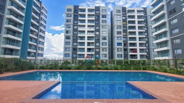 A modern apartment building with a swimming pool in the foreground. - Studio Apartment by Away Homes Rentals (Syokimau)