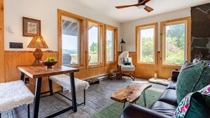 A cozy room with a wooden table, a chair, a sofa, and a ceiling fan. - Tiny Home with Spectacular Views & FP (Parksville)