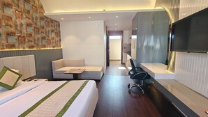 A modern hotel room with a large bed, a sofa, a desk, and a TV. - LivBox Dehradun (Dehradun)
