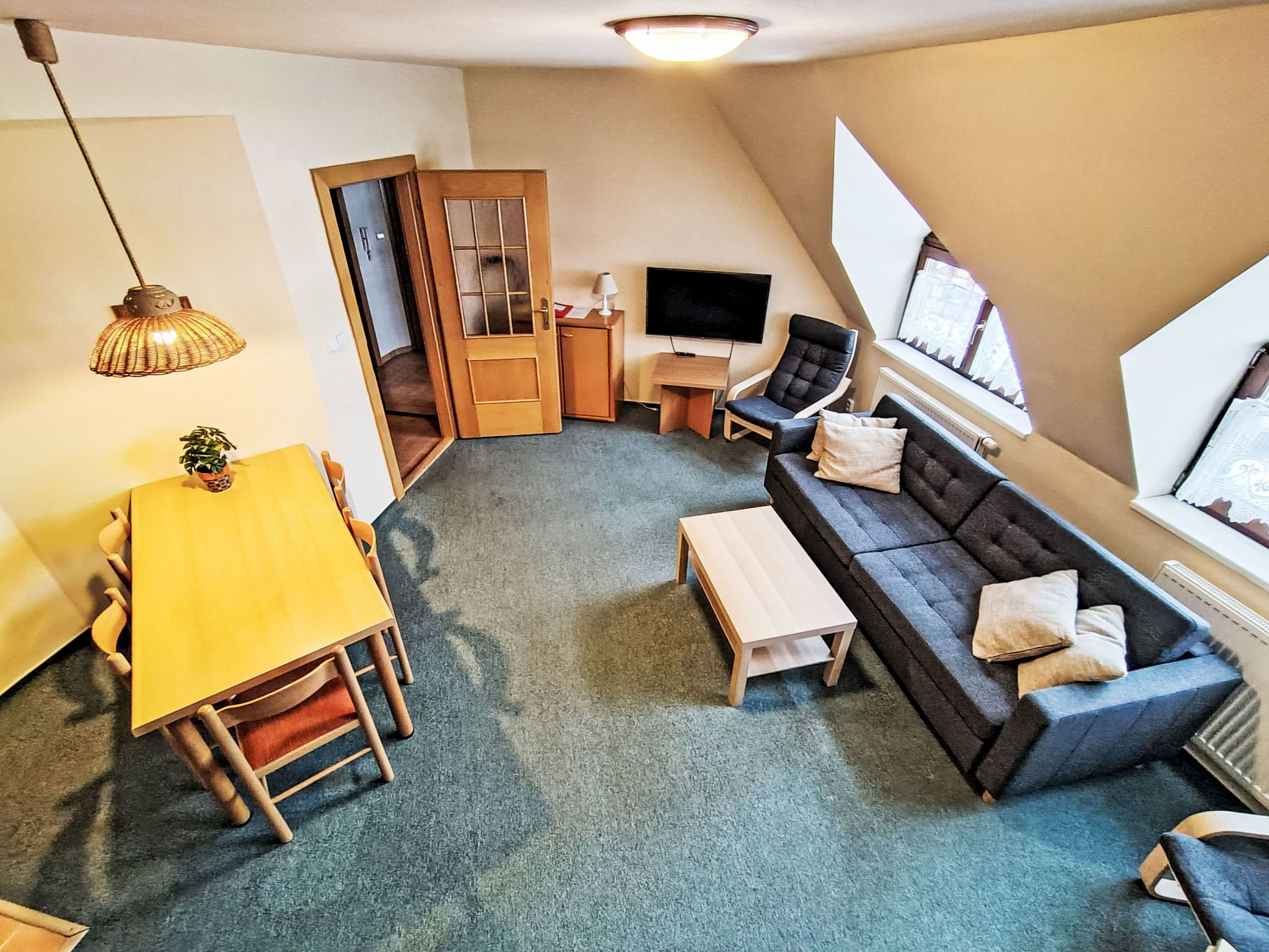 Ein gemütliches Wohnzimmer mit einer Couch, einem Couchtisch, einem Fernseher und einem Essbereich mit Tisch und Stühlen.