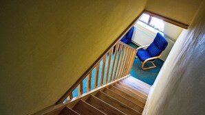 Un escalier en bois avec une chaise bleue en arrière-plan.