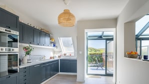 Une cuisine moderne avec des meubles de couleur sombre, une grande fenêtre et une vue sur l’extérieur.