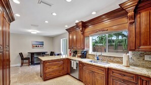 A kitchen with wooden cabinets, granite countertops, and a built-in dishwasher. - Stylish 2br/3ba w-Heated Pool + Beach Walkable (Lauderdale-by-the-Sea)