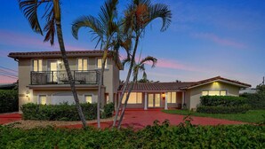 A two-story house with a balcony, a red driveway, and palm trees. - Stylish 2br/3ba w-Heated Pool + Beach Walkable (Lauderdale-by-the-Sea)