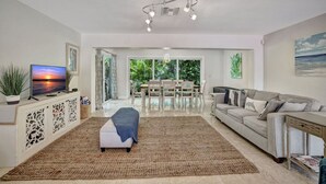 Un salon spacieux avec une grande télévision, un coin repas avec une table et des chaises, et un canapé.