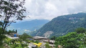 A mountainous landscape with a small settlement. - Hotel East Inn (Gangtok)