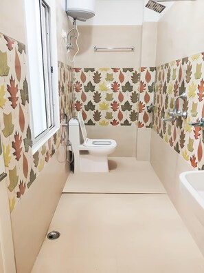 Et lille badeværelse med toilet, håndvask og brusebad.